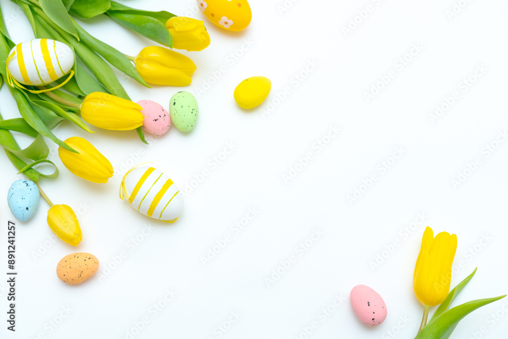 Yellow tulips and colorful Easter eggs are arranged on a white background. The concept of spring and Easter celebrations Yellow tulips and colorful Easter eggs are arranged on a white background. The concept of spring and Easter celebrations