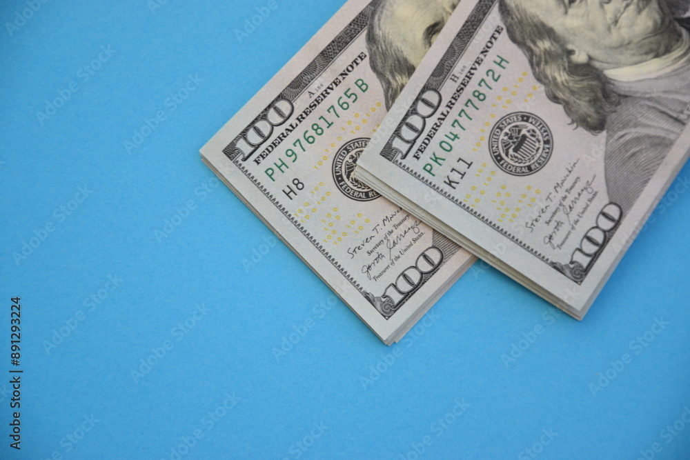 Bundles of one hundred dollar banknotes on blue background