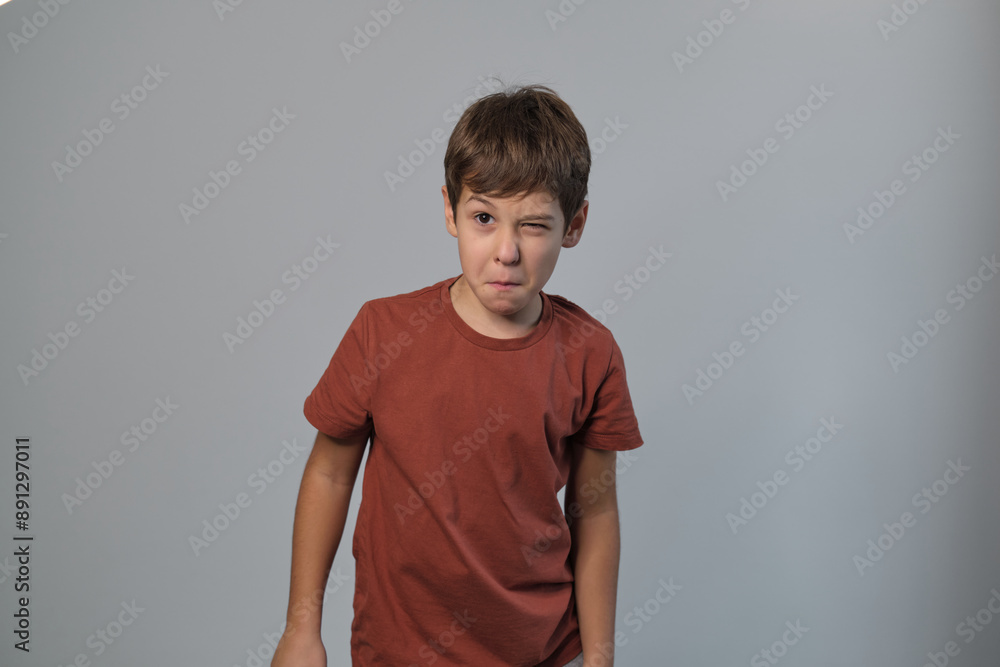 A frustrated young boy with attitude is positioned in front of a plain gray backdrop A frustrated young boy with attitude is positioned in front of a plain gray backdrop