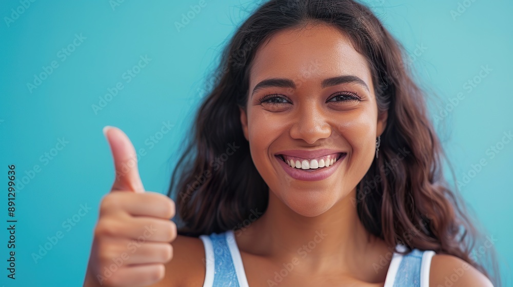a confident young woman giving a thumbs-up, smiling brightly, against a blue background that enhances her positive and successful demeanor a confident young woman giving a thumbs-up, smiling brightly, against a blue background that enhances her positive and successful demeanor