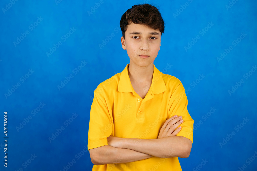 Close-up portrait of a young man, a teenager on a blue background, sad, look at the camera