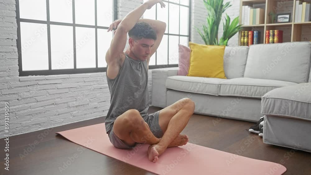 A toned young hispanic man stretching on a pink yoga mat in a stylish living room, exuding wellness and tranquility. A toned young hispanic man stretching on a pink yoga mat in a stylish living room, exuding wellness and tranquility.