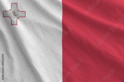 Malta flag depicted on folded wavy fabric of old cloth close up photo