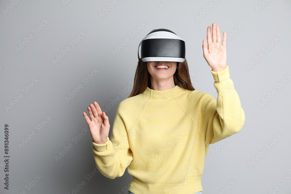 Smiling woman using virtual reality headset on light grey background Smiling woman using virtual reality headset on light grey background