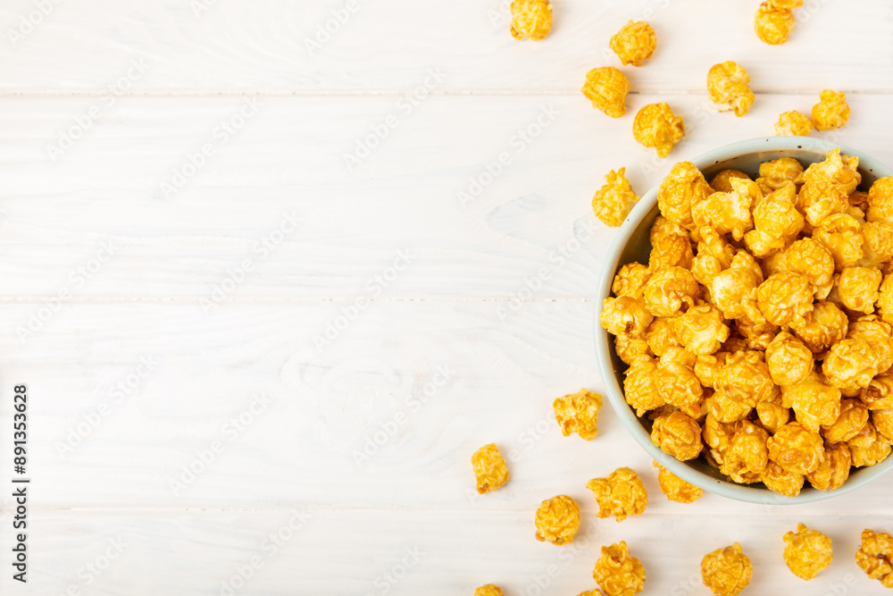 Sweet caramel popcorn in a bowl on a wooden background. Salted caramel popcorn. Caramel sauce. Close up. Topping. Place for text. Copy space Sweet caramel popcorn in a bowl on a wooden background. Salted caramel popcorn. Caramel sauce. Close up. Topping. Place for text. Copy space