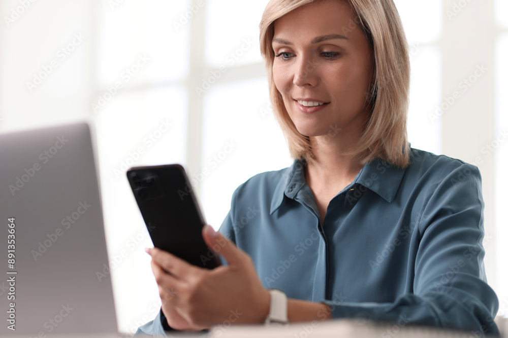 Happy woman using mobile phone at white table indoors Happy woman using mobile phone at white table indoors