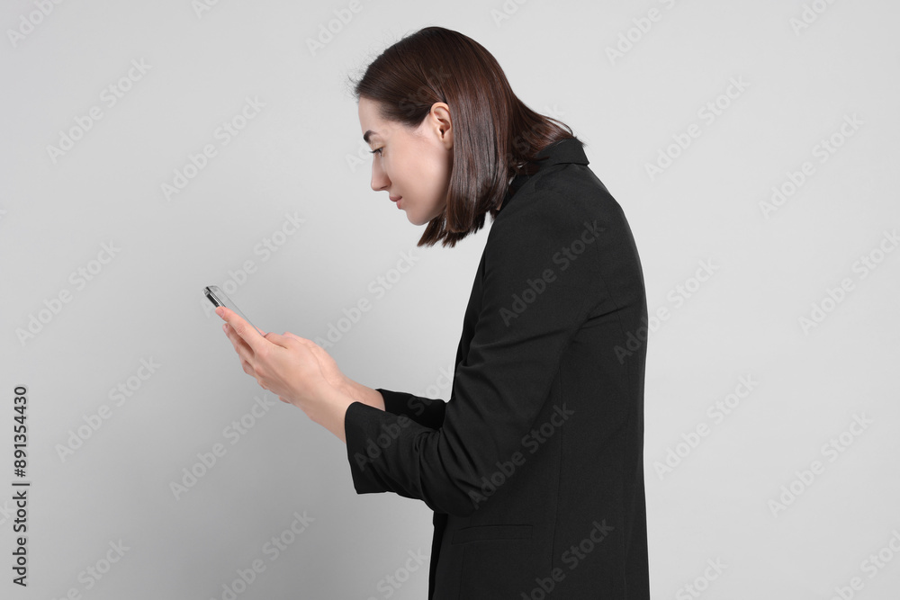 Woman with poor posture using smartphone on gray background Woman with poor posture using smartphone on gray background
