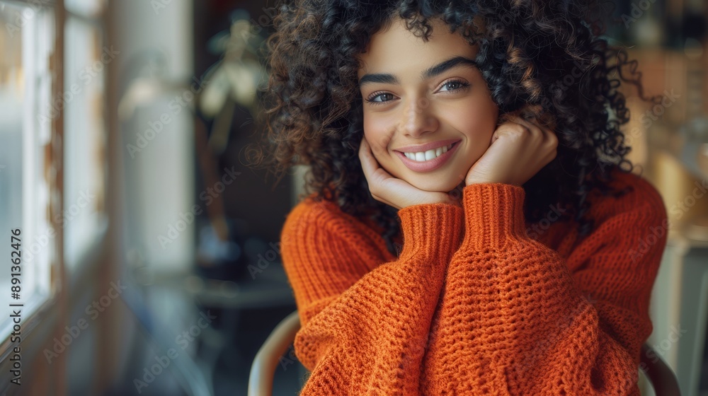 A woman with curly hair is smiling and wearing an orange sweater A woman with curly hair is smiling and wearing an orange sweater
