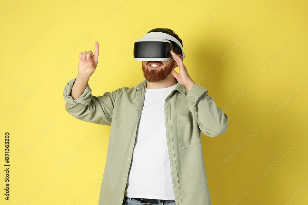 Happy man using virtual reality headset on pale yellow background Happy man using virtual reality headset on pale yellow background