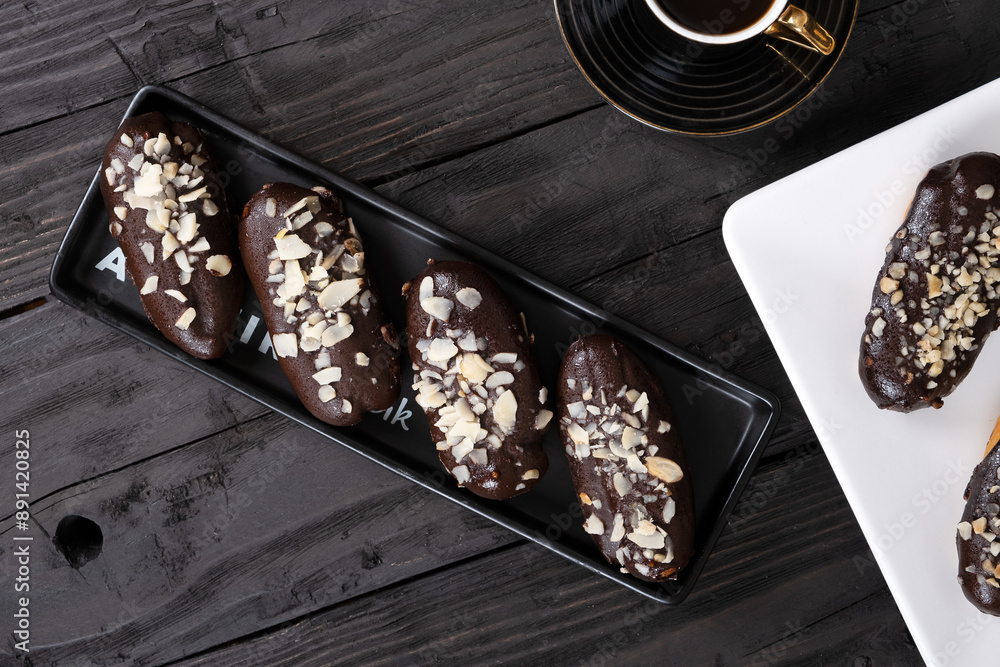 Chocolate Eclairs on White Plate with Coffee Cup: Delicious French Pastries and Hot Beverage for Gourmet Dessert or Cafe Menu Background Chocolate Eclairs on White Plate with Coffee Cup: Delicious French Pastries and Hot Beverage for Gourmet Dessert or Cafe Menu Background