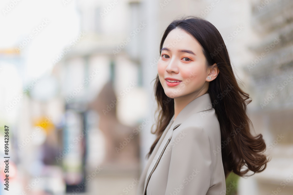 Picture of beautiful long haired young Asian girl in cream blazer suit smiling happily walking and looking out in the city outdoors. Picture of beautiful long haired young Asian girl in cream blazer suit smiling happily walking and looking out in the city outdoors.