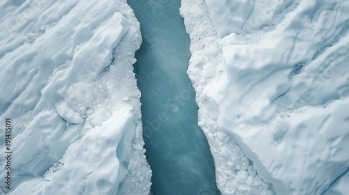 An aerial capture of a frozen landscape split by a central icy blue water channel, highlighting the stark contrast between rugged ice formations and the fluid water path. photo