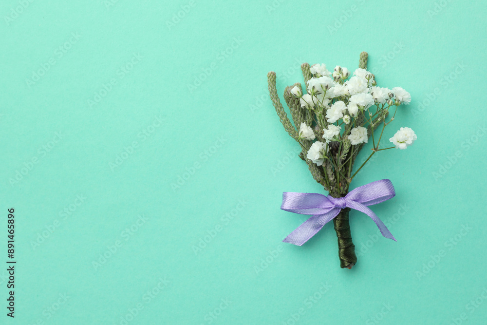 Small stylish boutonniere on turquoise background, flat lay. Space for text Small stylish boutonniere on turquoise background, flat lay. Space for text