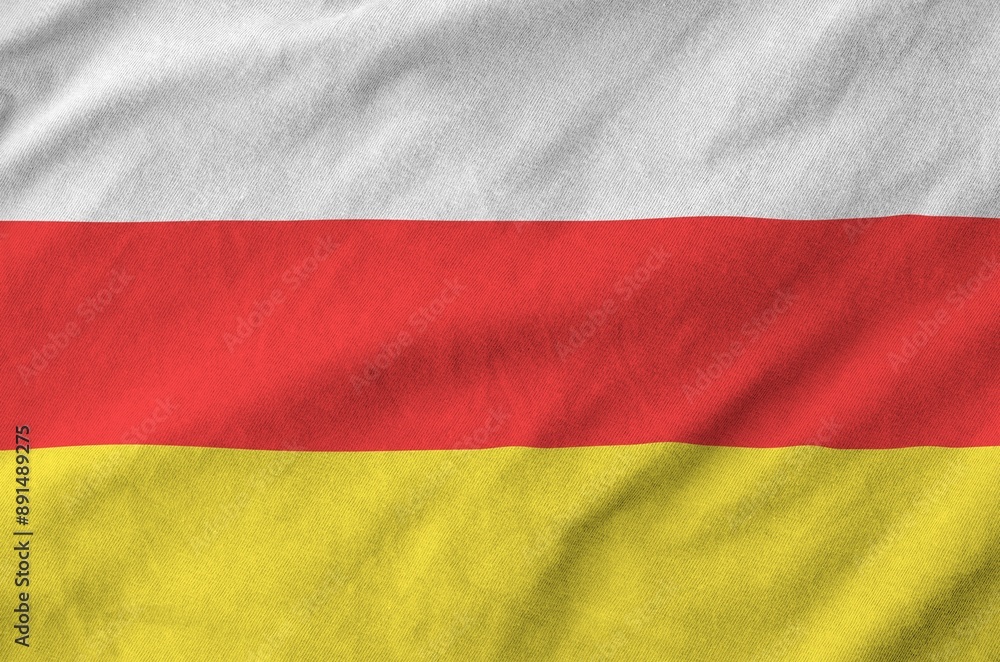 Naklejka premium South Ossetia flag depicted on folded wavy fabric of old cloth close up