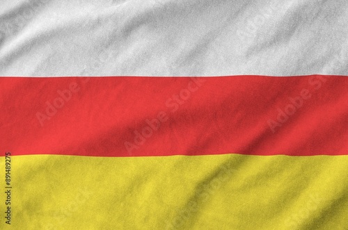 South Ossetia flag depicted on folded wavy fabric of old cloth close up photo