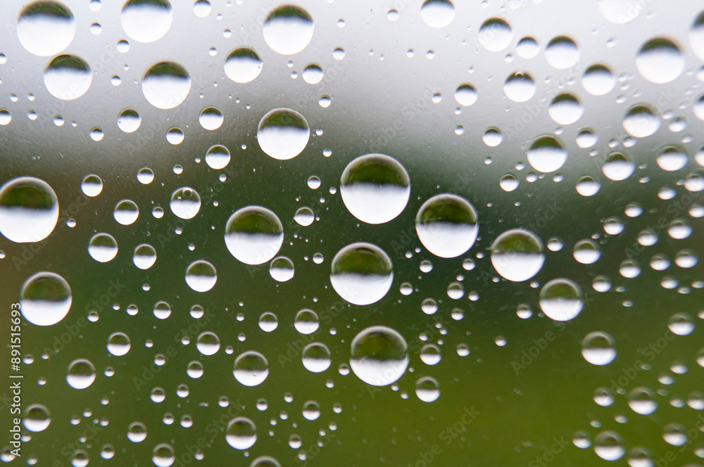 Straight view of water droplets on clear glass on blurred nature background. Suitable for design and wallpaper.