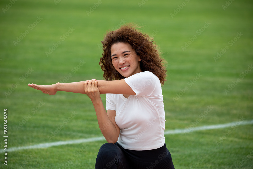 Curly beautiful Asian girl in a white T-shirt and black leggings plays sports on the football field Curly beautiful Asian girl in a white T-shirt and black leggings plays sports on the football field