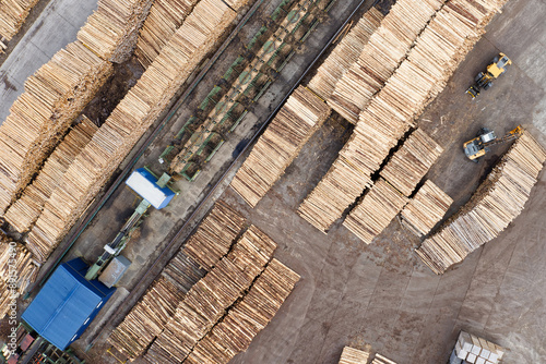 Sawmill with chopped wood logs stacked and machinery photo