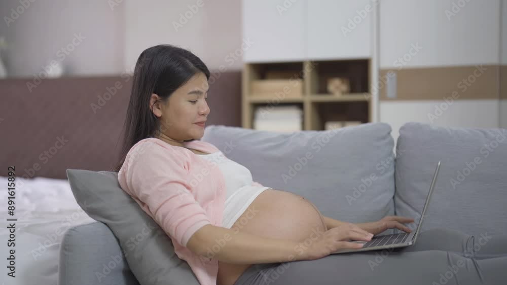 A portrait of happy Asian pregnant woman using, working online with computer laptop notebook tablet device with screen in bedroom at home. Having a baby. Family people lifestyle. Mom love.
