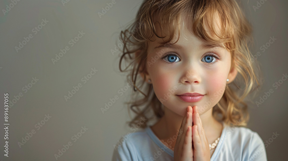 A kid praying and looking at the camera on plain background, symbolizing faith in god. A kid praying and looking at the camera on plain background, symbolizing faith in god.