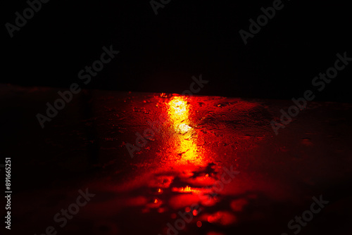 Obraz na płótnie Red light is reflected in the water during the night. The scene is dark and moody. Red light shining through rain on dark surface, creating a moody and atmospheric scene w salonie