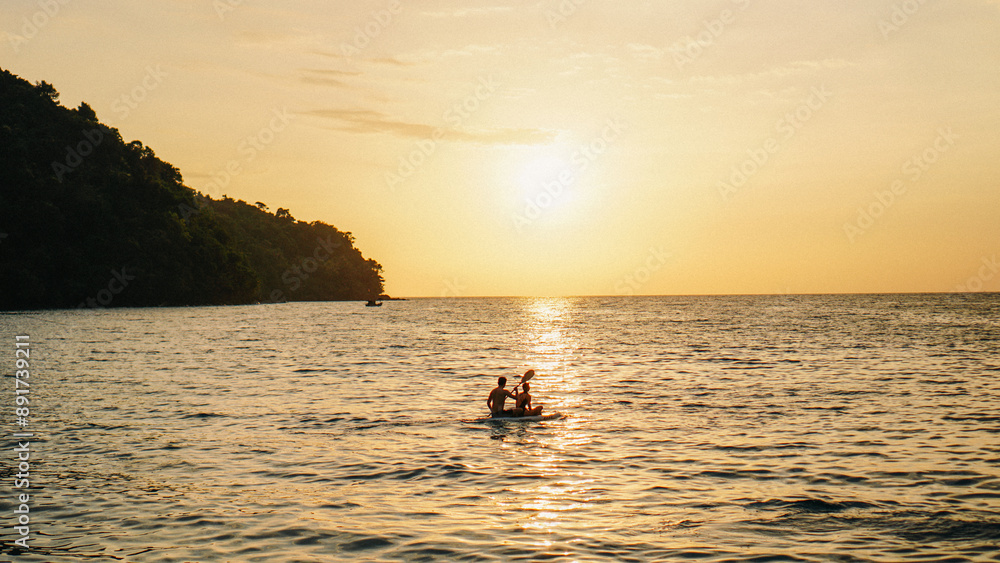 Fototapeta premium Kayak on the beach at sunset. Thailand. Exotic Sunset Beach and Calm Seascape for Summer. Couple kayaking at sunset by the sea. Canoe on the ocean beach during the amazing sunset.