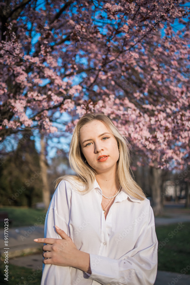 Fashion outdoor photo of beautiful woman with blond hair in elegant suit posing in spring flowering park with blooming cherry tree. Copy space and empty place for advertising text Fashion outdoor photo of beautiful woman with blond hair in elegant suit posing in spring flowering park with blooming cherry tree. Copy space and empty place for advertising text