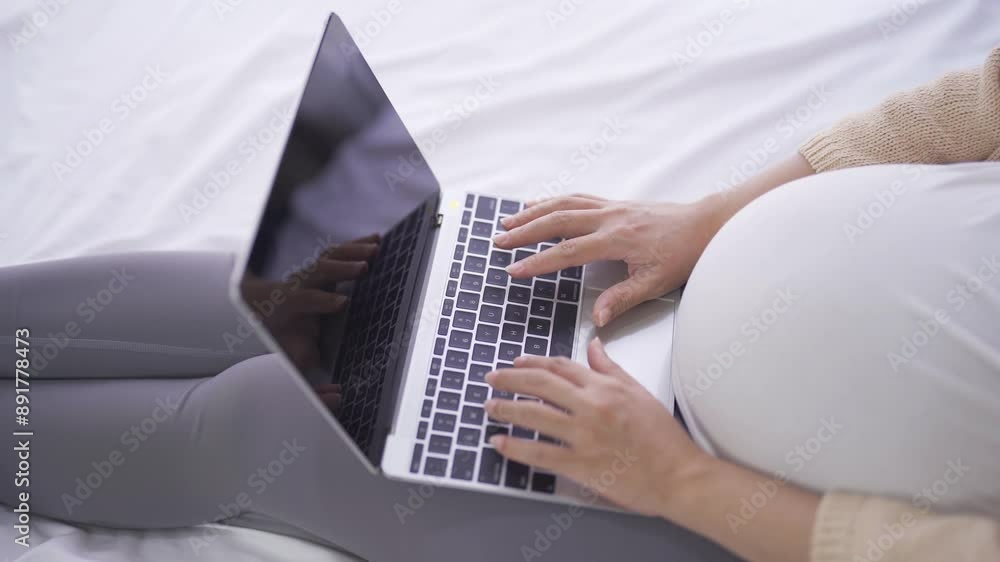 A portrait of happy Asian pregnant woman using, working online with computer laptop notebook tablet device with screen in bedroom at home. Having a baby. Family people lifestyle. Mom love. A portrait of happy Asian pregnant woman using, working online with computer laptop notebook tablet device with screen in bedroom at home. Having a baby. Family people lifestyle. Mom love.