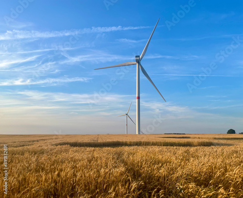 Wind turbines against the backdrop of sunset over a wheat field