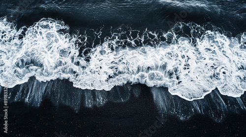 top view of ocean waves with white foam and black sand, aerial view 