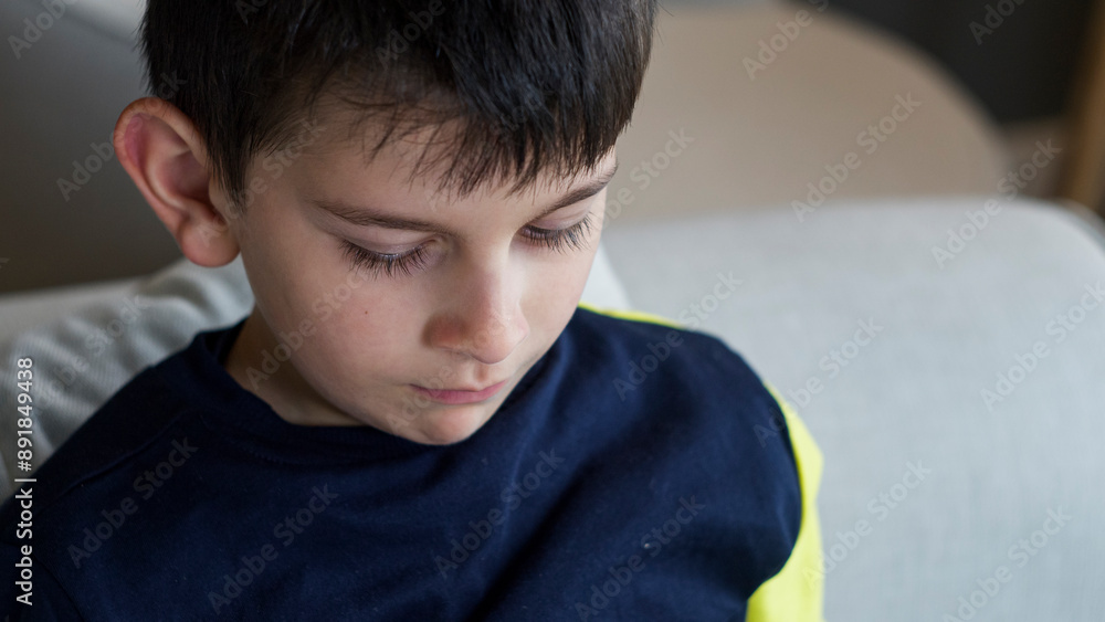 A close-up shot of a young boy looking down with a serene and focused expression. A close-up shot of a young boy looking down with a serene and focused expression.