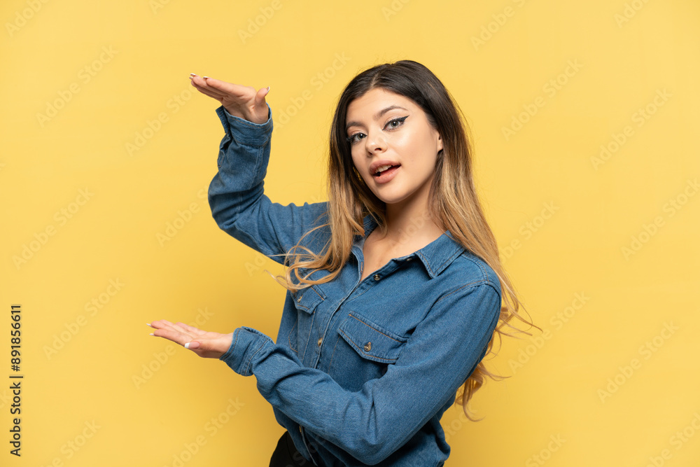 Young Russian girl isolated on yellow background holding copyspace to insert an ad Young Russian girl isolated on yellow background holding copyspace to insert an ad