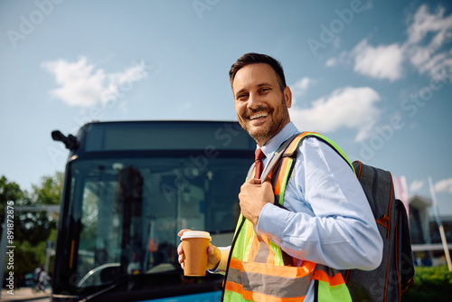 Happy bus driver with takeaway coffee coming to work at looking at camera. photo