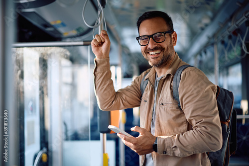 Foto Happy man texting on mobile phone while commuting by bus and looking at camera
