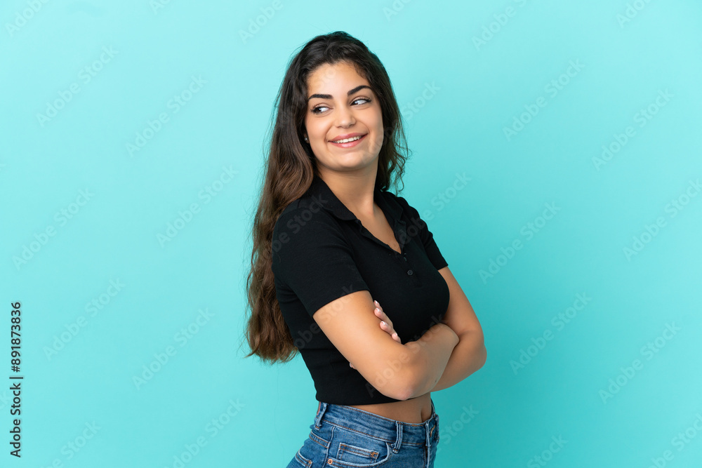 Young caucasian woman isolated on blue background with arms crossed and happy Young caucasian woman isolated on blue background with arms crossed and happy