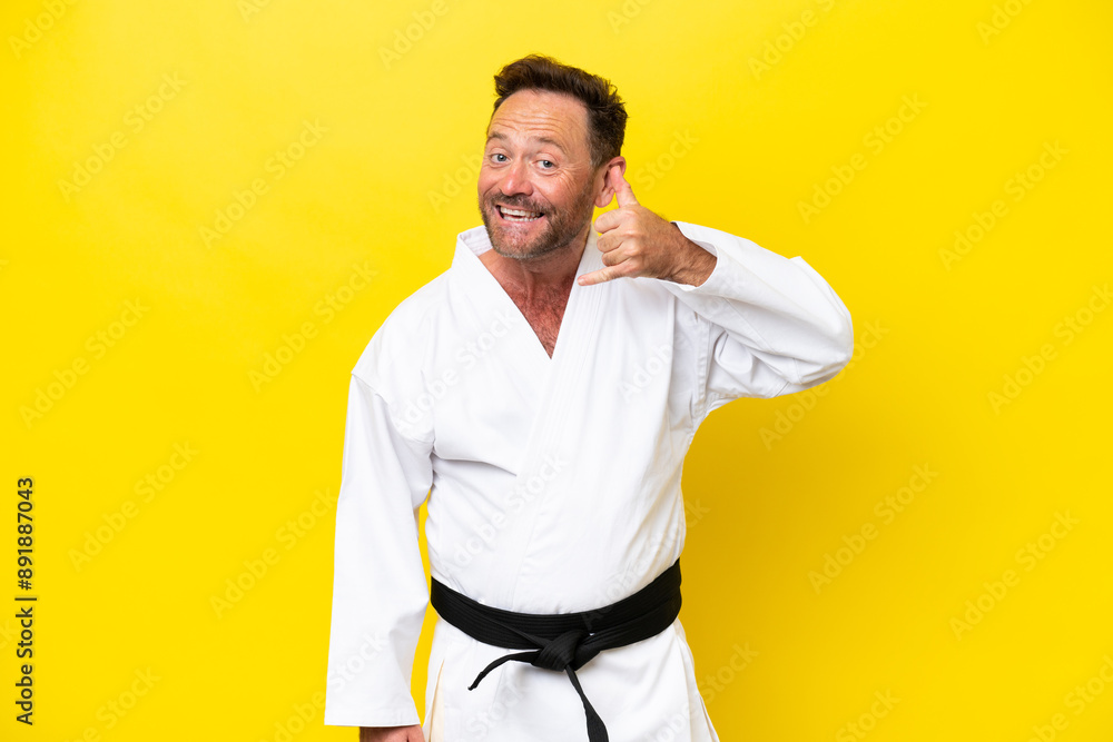 Middle age caucasian man doing karate isolated on yellow background making phone gesture. Call me back sign Middle age caucasian man doing karate isolated on yellow background making phone gesture. Call me back sign