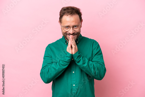 Middle age caucasian man isolated on pink background keeps palm together. Person asks for something