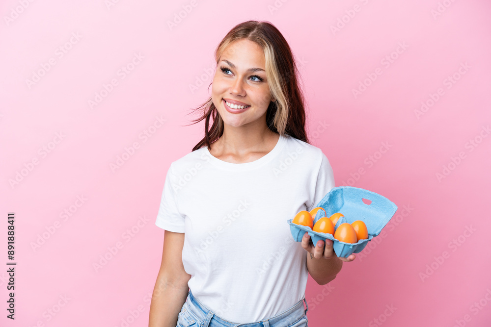Young Russian woman holding eggs isolated on pink background looking to the side and smiling Young Russian woman holding eggs isolated on pink background looking to the side and smiling