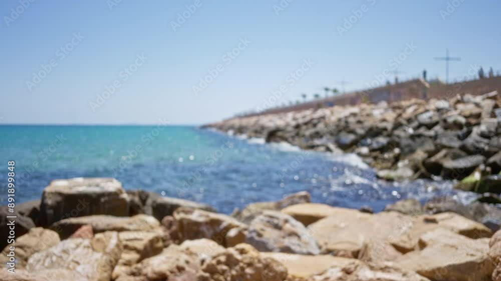Blurred ocean coastline with rocky shore under clear blue sky Blurred ocean coastline with rocky shore under clear blue sky