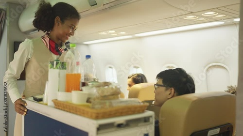 Air hostess haul trolley in the airplane during service of food and drinking to the passenger.