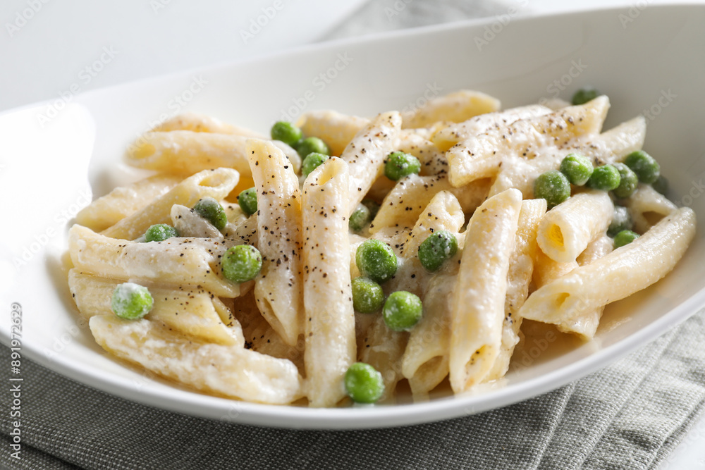 Delicious pasta with green peas and creamy sauce in bowl on table, closeup Delicious pasta with green peas and creamy sauce in bowl on table, closeup