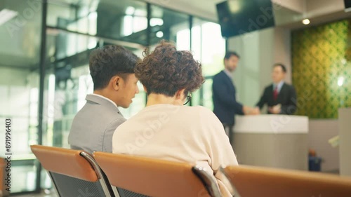 Back of two Asian man and woman sit and talk toogether in front of service counter in the airport. photo