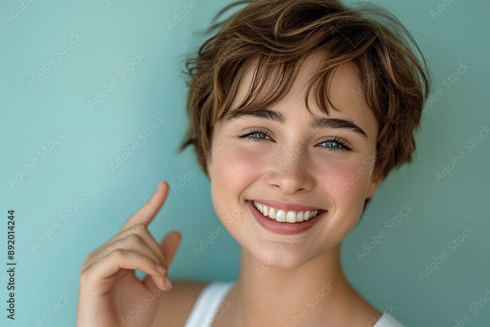 Smiling Young Woman with Short Hair Touching Cheek Against Light Blue Background Smiling Young Woman with Short Hair Touching Cheek Against Light Blue Background