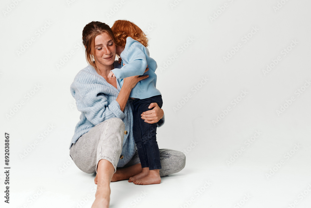 Mother and daughter in matching blue pajamas sitting together on floor, family bonding and relaxation concept Mother and daughter in matching blue pajamas sitting together on floor, family bonding and relaxation concept
