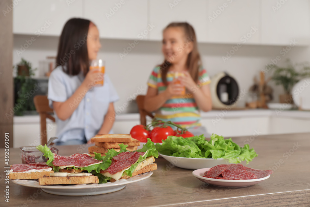 Tasty toasts with sausages and salad on table in kitchen, closeup Tasty toasts with sausages and salad on table in kitchen, closeup
