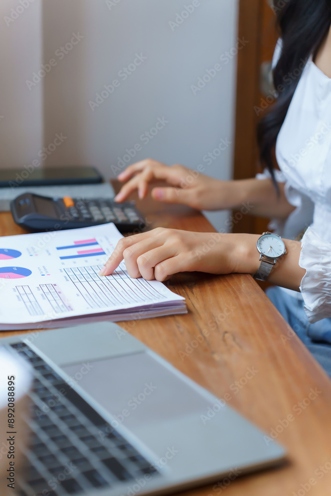 Fototapeta premium Closeup hands of young asian businesswoman pointing on document to checking financial data with calculator while thinking about investment and planning of new startup project for working in cafe