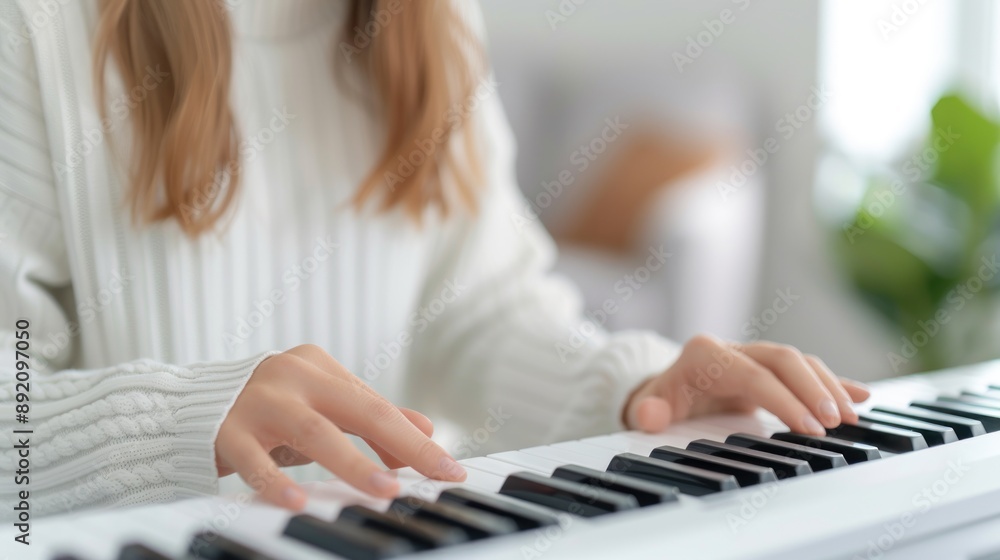 Fototapeta premium Young woman sitting and playing keyboard, free time, hobbies and playing music.