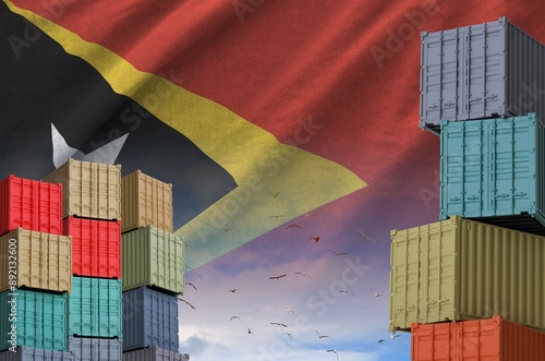 Timor Leste flag and big stack of shipping cargo containers in docks with sky background close up photo