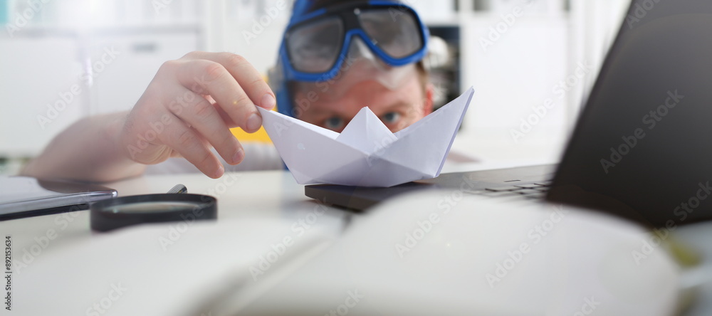 Man wearing suit and tie in goggles and snorkel play with paper ship in office closeup. Count days to leave annual day off workaholic freedom fun tourism resort idea ticket sale concept Man wearing suit and tie in goggles and snorkel play with paper ship in office closeup. Count days to leave annual day off workaholic freedom fun tourism resort idea ticket sale concept
