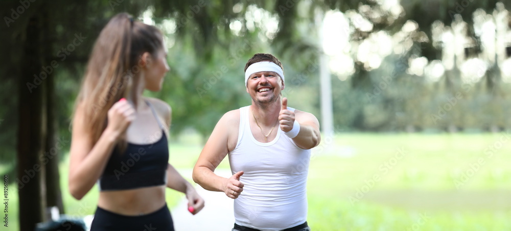 Fatty millennial man running in park with girlfriend willing to get slim and fit portrait. Healthy leisure and sportsman life and hard work concept Fatty millennial man running in park with girlfriend willing to get slim and fit portrait. Healthy leisure and sportsman life and hard work concept